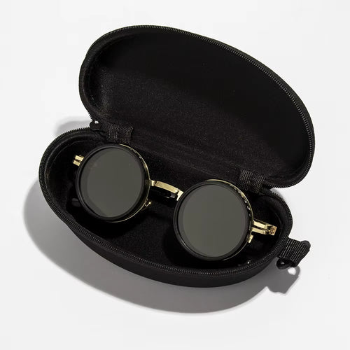Black sunglasses with gold frames in an open black case on a white background